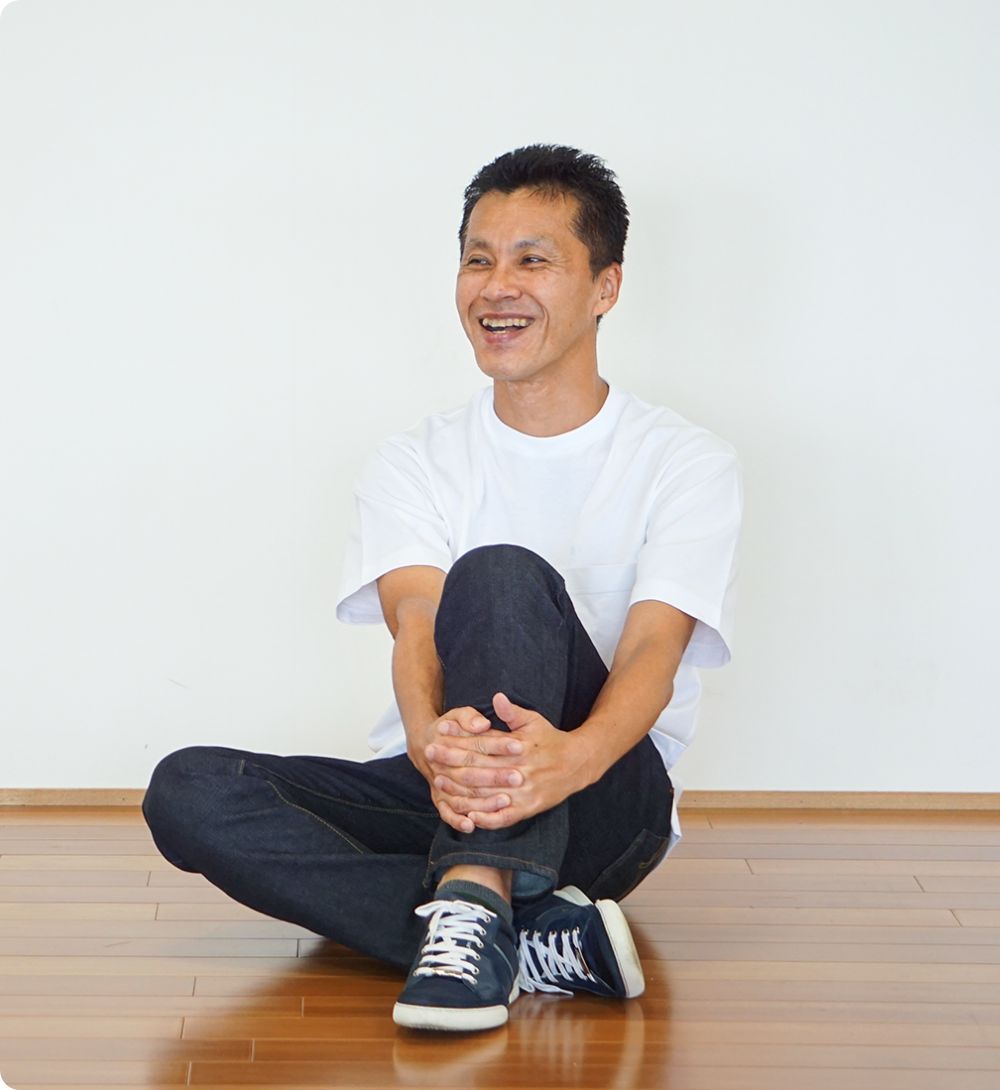 笑顔で座りながら話す平谷代表