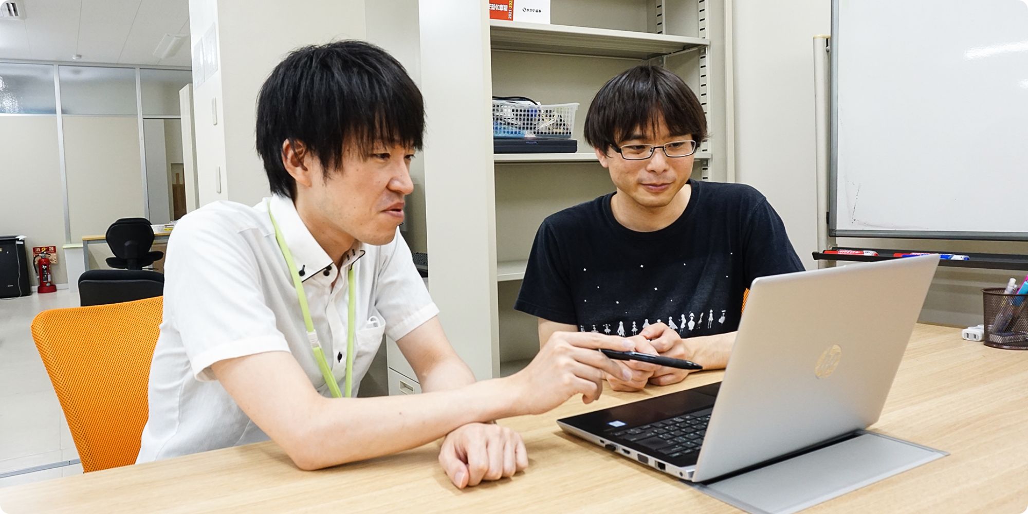 社内スタッフとパソコンを見て会話する朝日さんの様子